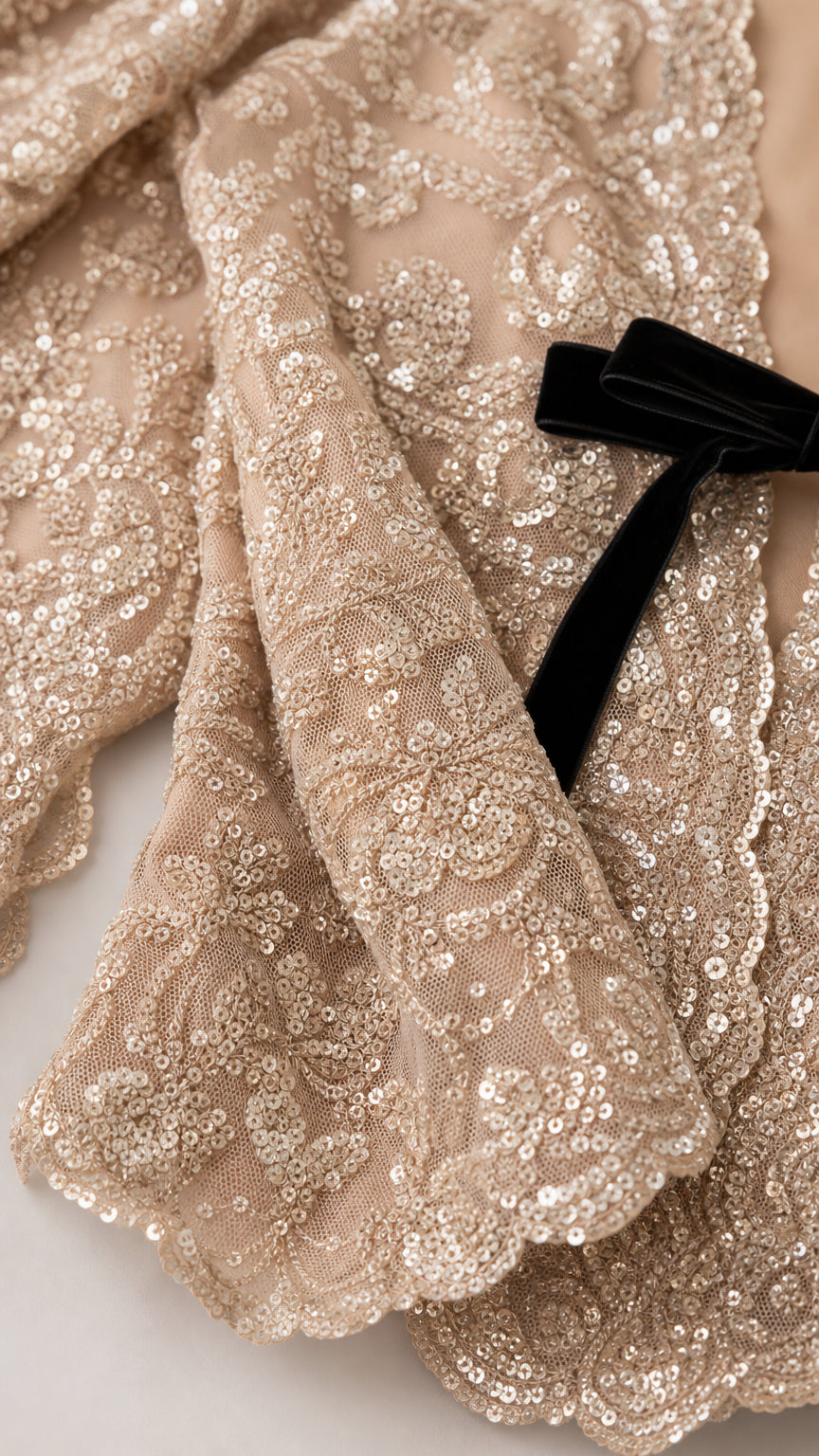 Close-up detail of sequin lace fabric and black velvet bow