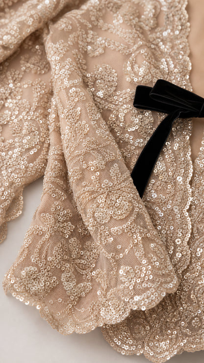 Close-up detail of sequin lace fabric and black velvet bow