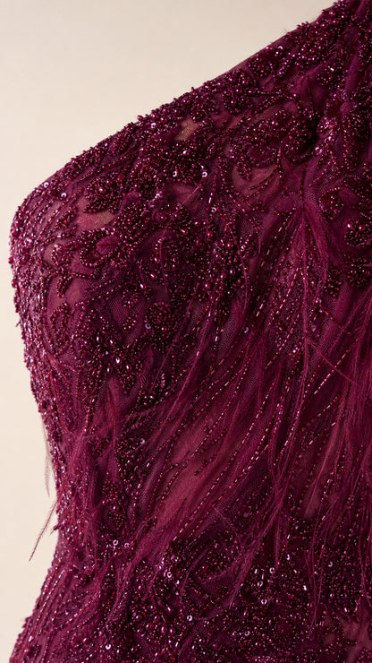 Close-up of intricate beadwork and feather texture on burgundy gown