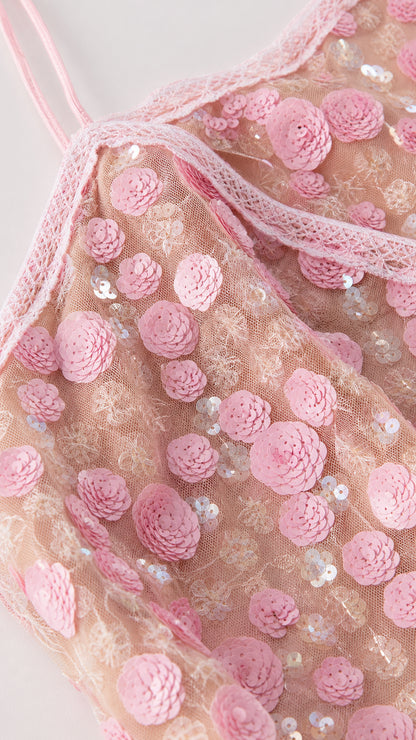 Close-up detail of pink dress bodice with floral appliques and straps
