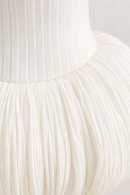 Close-up detail of fine vertical pleats and textured bubble hem