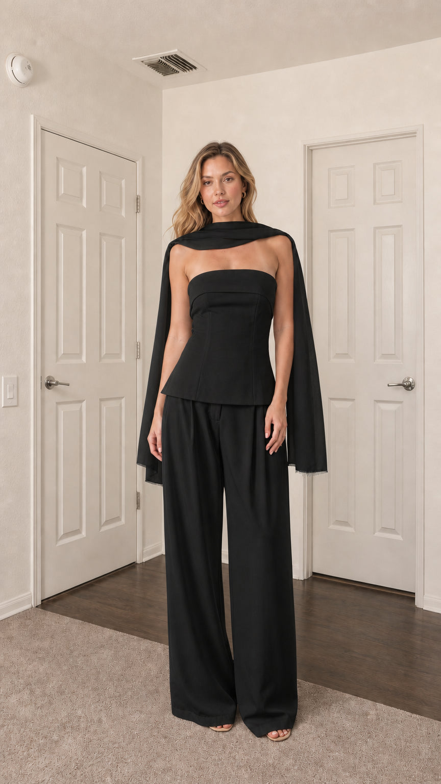 Front view of model wearing black strapless top, wide-leg pants, and scarf