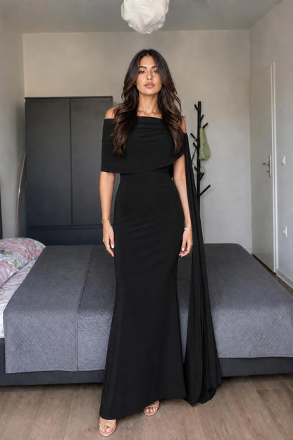 Model wearing black off-shoulder cape maxi dress