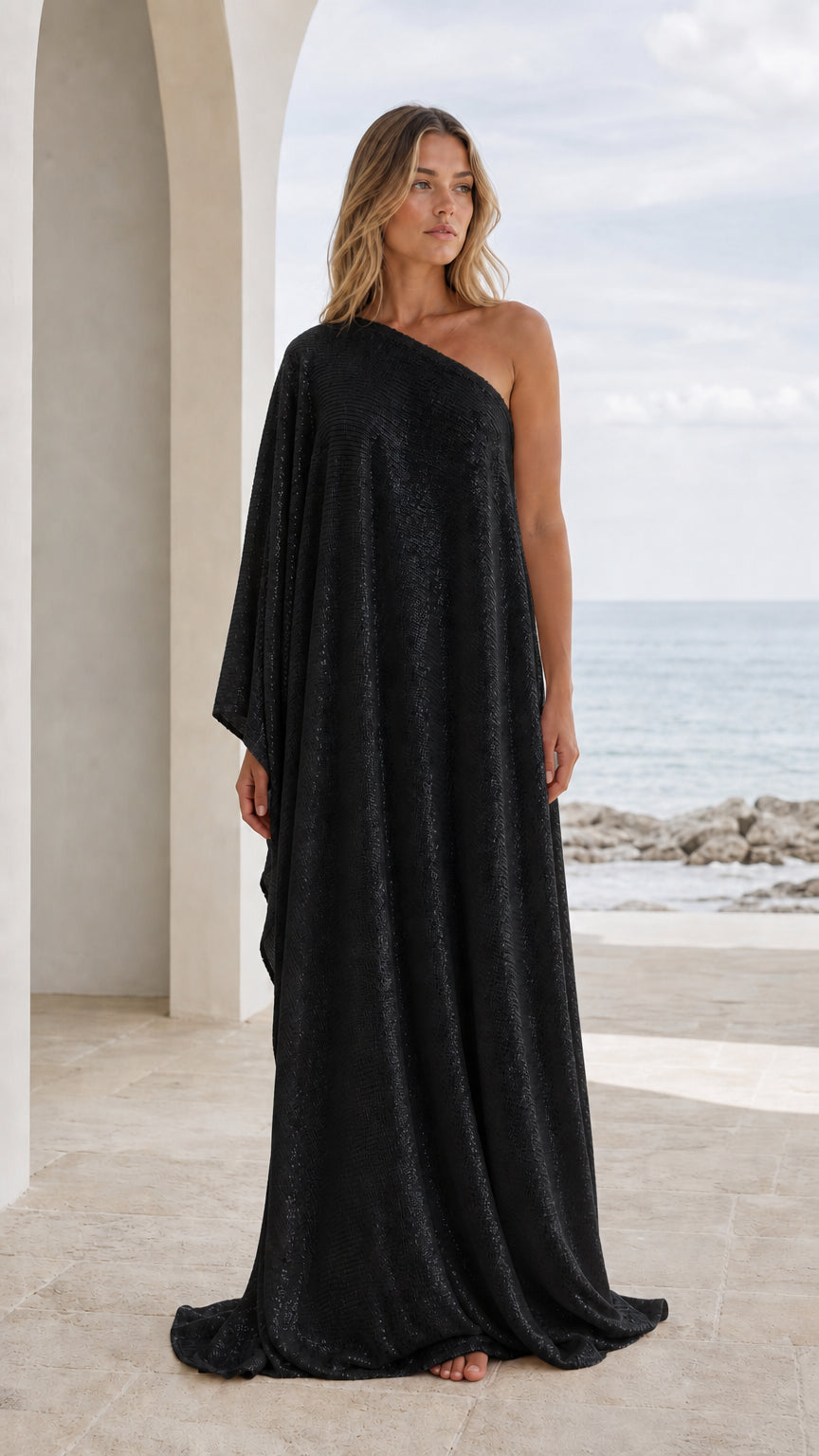 Front view of woman wearing black one-shoulder draped maxi kaftan dress