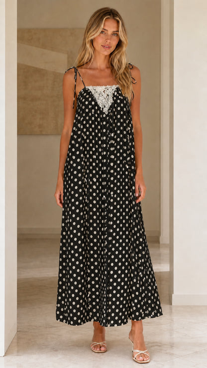 Front view of woman wearing black polka dot maxi dress