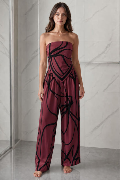 Woman wearing burgundy and black abstract print strapless jumpsuit