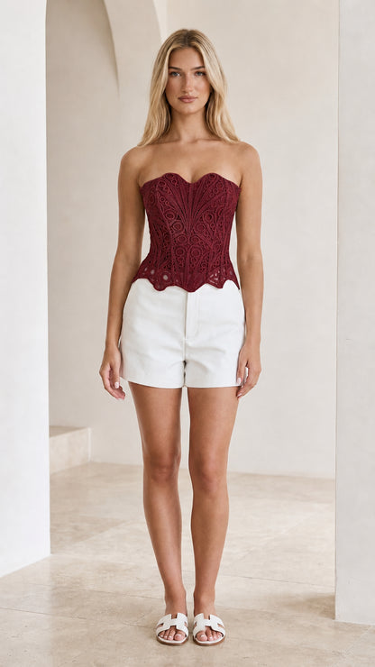 Front view of woman wearing burgundy strapless crochet lace corset top
