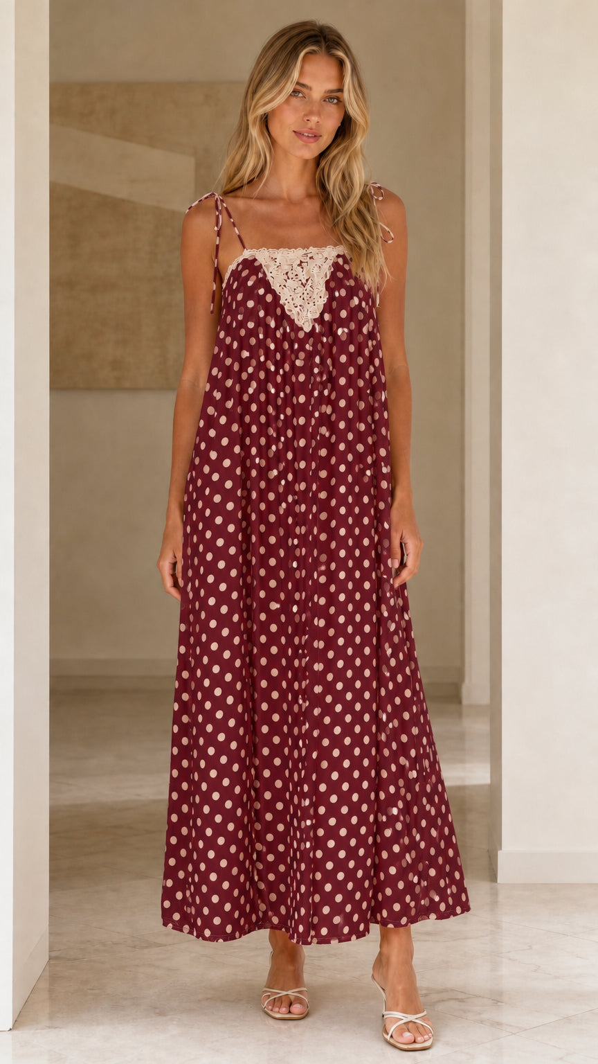 Front view of woman wearing burgundy polka dot maxi dress
