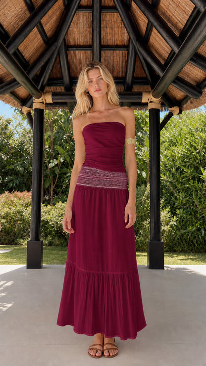 Woman wearing burgundy strapless tiered maxi dress
