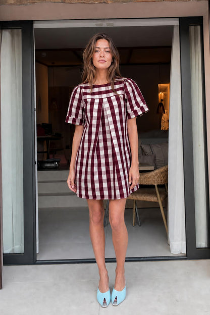 Front view of woman wearing burgundy gingham check mini dress